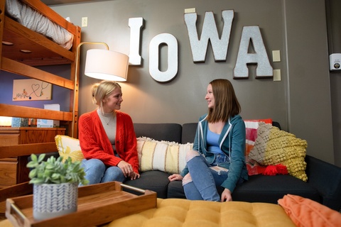 Two students sitting on a couch in a dorm room