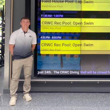 image of Dalton standing in front of the schedule display at the CRWC