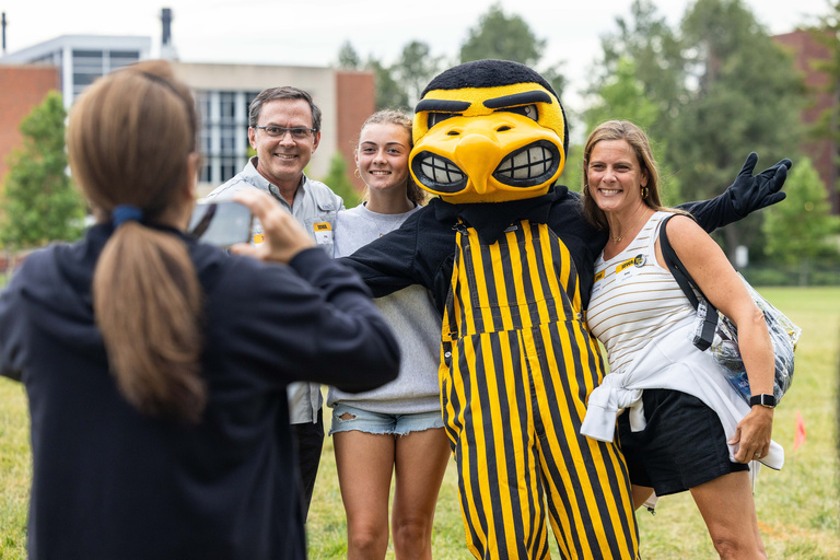 family taking photos with Herky during Family Weekend