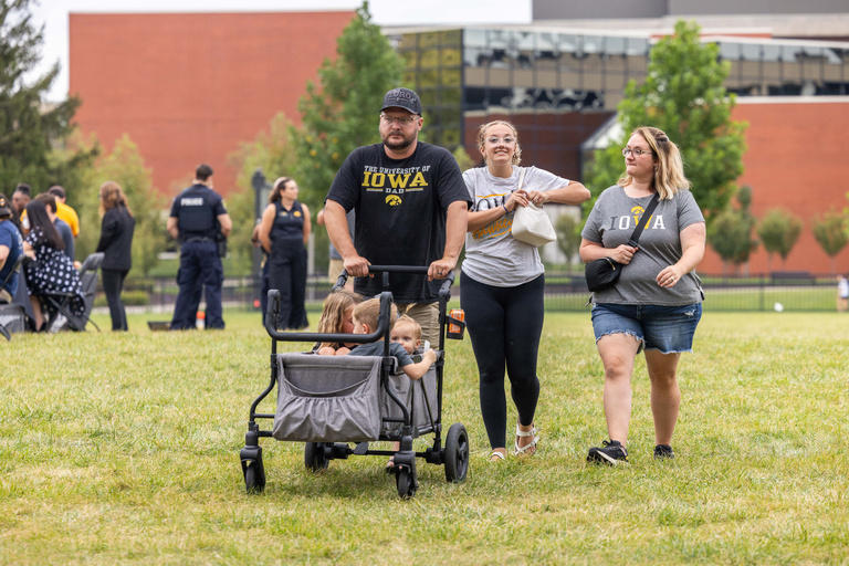 family with a stroller walking in a park in iowa city