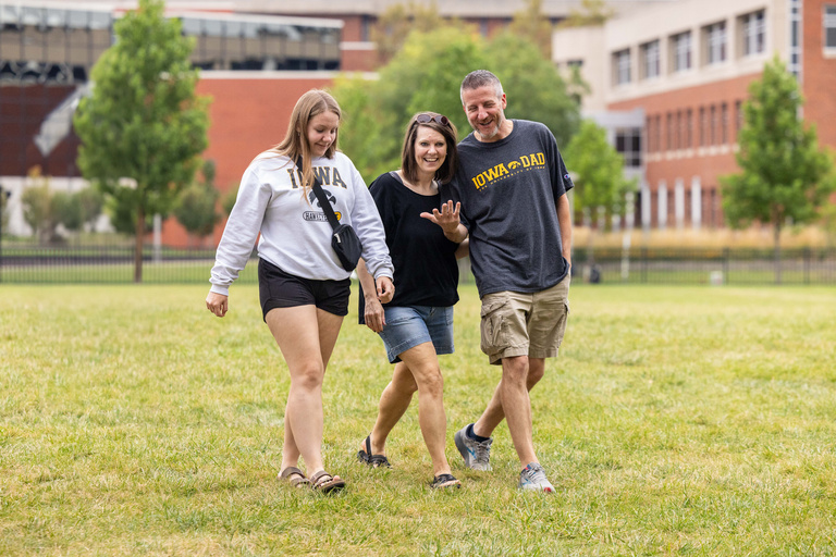 family walking in the grass at the university of iowa campus