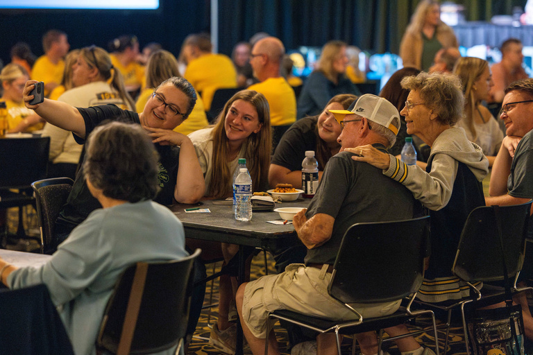 Family sitting a table taking a selfie during Family Weekend